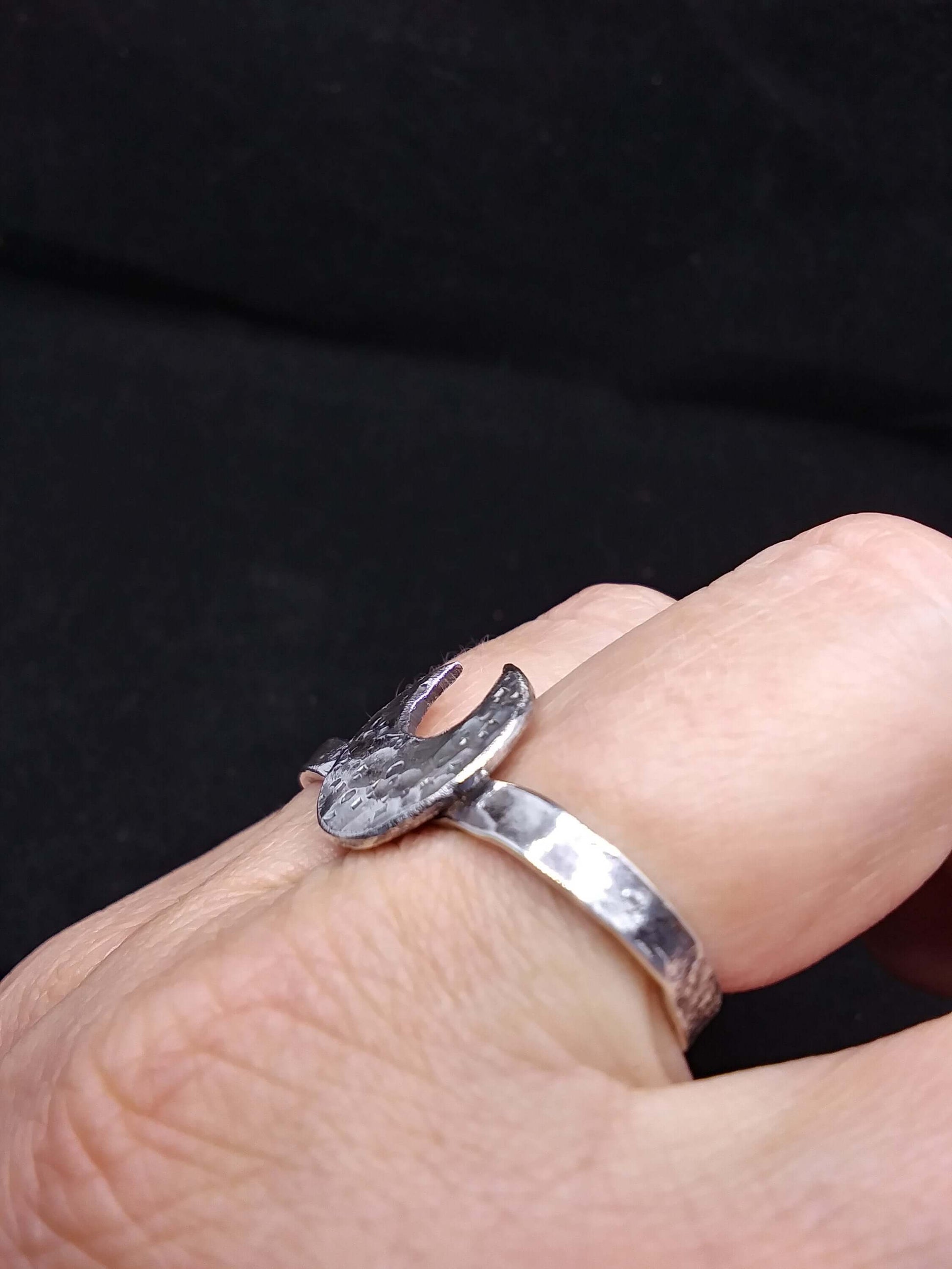 Side view of a silver double ring with a crescent moon on splayed fingers.